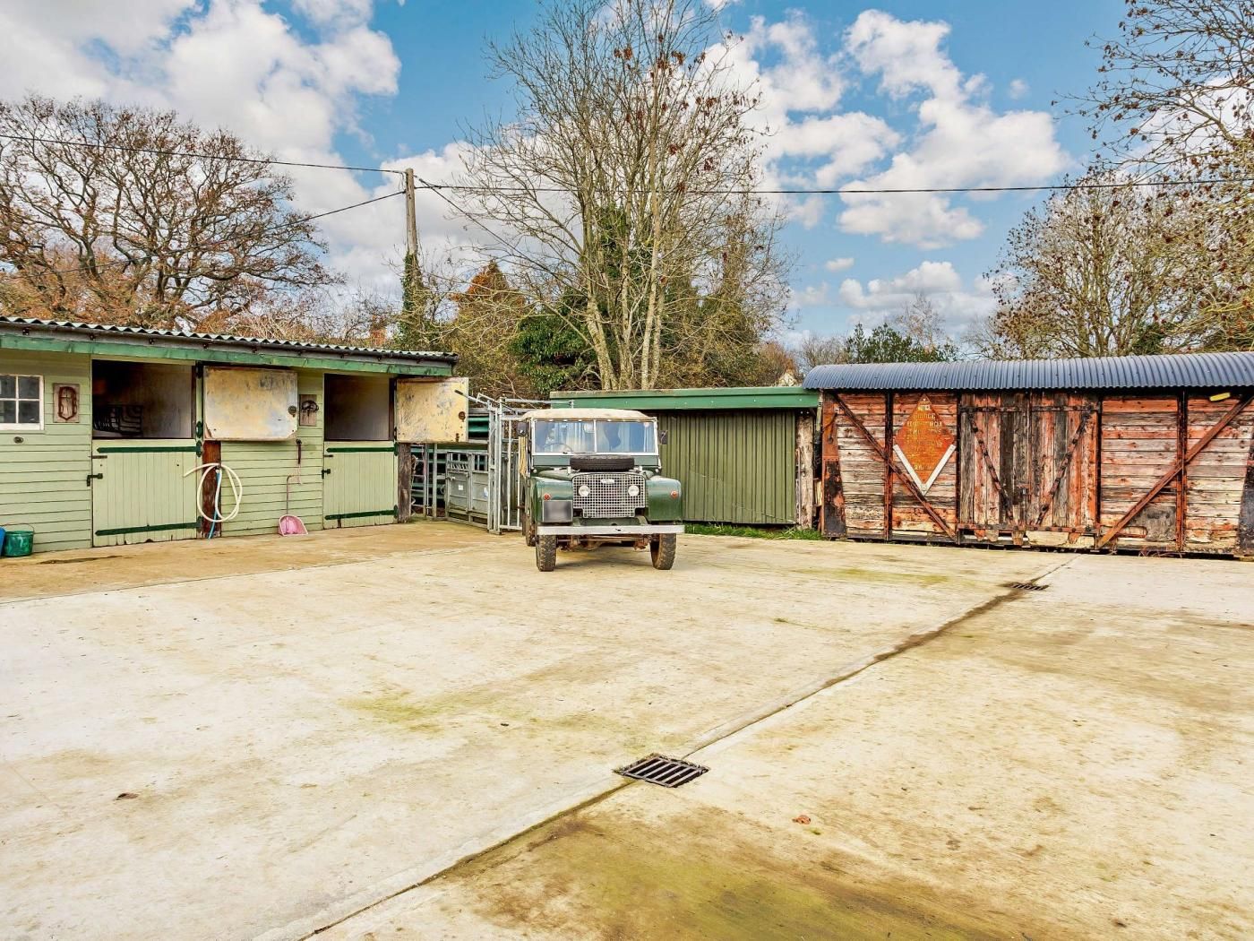A green building with a garage, a truck, and a wooden shed.