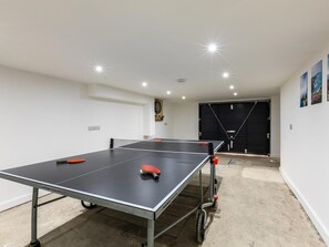 A ping pong table in a room with a black door, a dartboard, and a wall with framed pictures. - 5 Bed in Fowey (oc-93849) (Polruan)