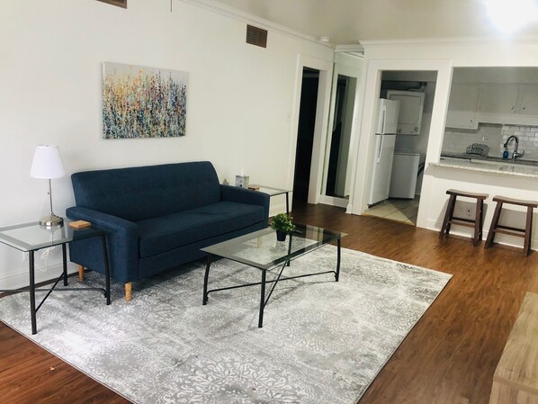 A living room with a sofa, coffee table, and a painting on the wall.