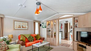 A modern living room with a sofa, coffee table, TV, and wooden cabinets. - 2 Bed in Sandown (oc-93900) (Sandown)