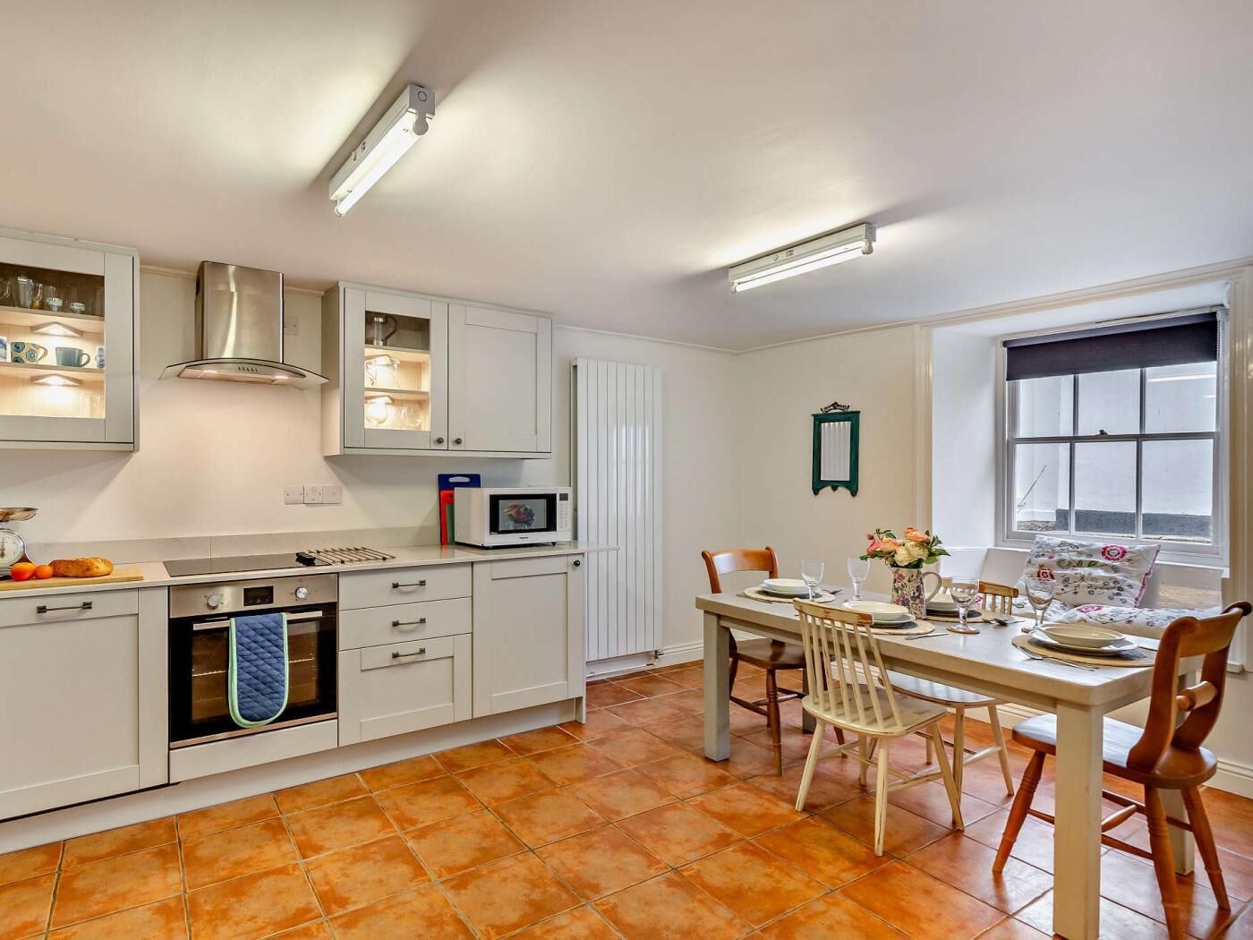 A kitchen with white cabinets, a microwave, a stove, and a dining area with a table and chairs.