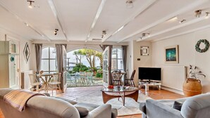 Un salón comedor amplio con televisor, asientos cómodos y vistas a través de un ventanal grande.