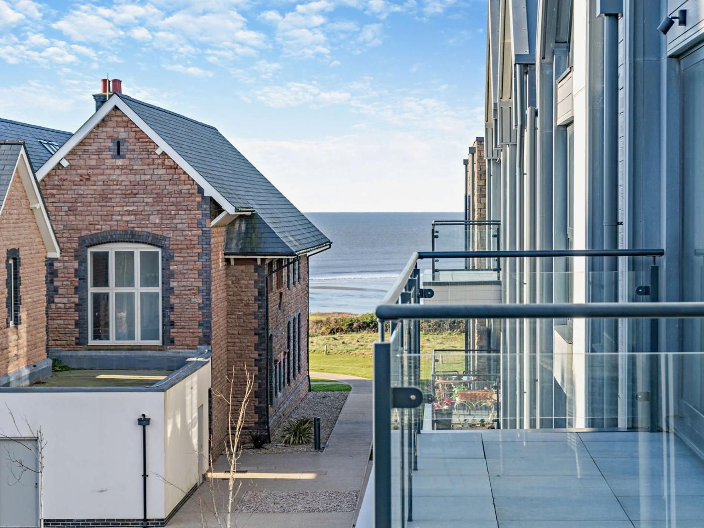 Un bâtiment moderne doté d’un balcon en verre offrant une vue sur la côte.