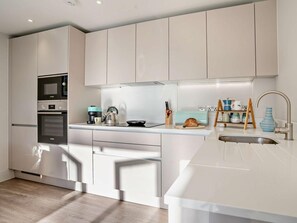 Una cocina moderna con electrodomésticos de acero inoxidable, una isla central con pileta y una tabla de cortar de madera.