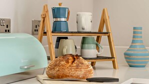 Un comptoir de cuisine avec une miche de pain, une machine à café et un vase.