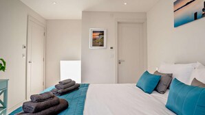 Une chambre d’hôtel avec un lit, une table de chevet, un tableau accroché au mur et une porte.