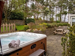 A hot tub in a garden with stone walls, a wooden fence, and a picnic table. - 7 Bed in Buxton (oc-93808) (Tideswell)