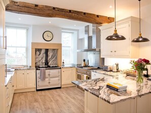 A modern kitchen with white cabinetry, a marble countertop, a clock, and pendant lighting. - 7 Bed in Buxton (oc-93808) (Tideswell)