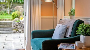 Een gezellige kamer met een blauwgroene bank, een vloerlamp, een potplant en een tijdschrift op een houten tafel.