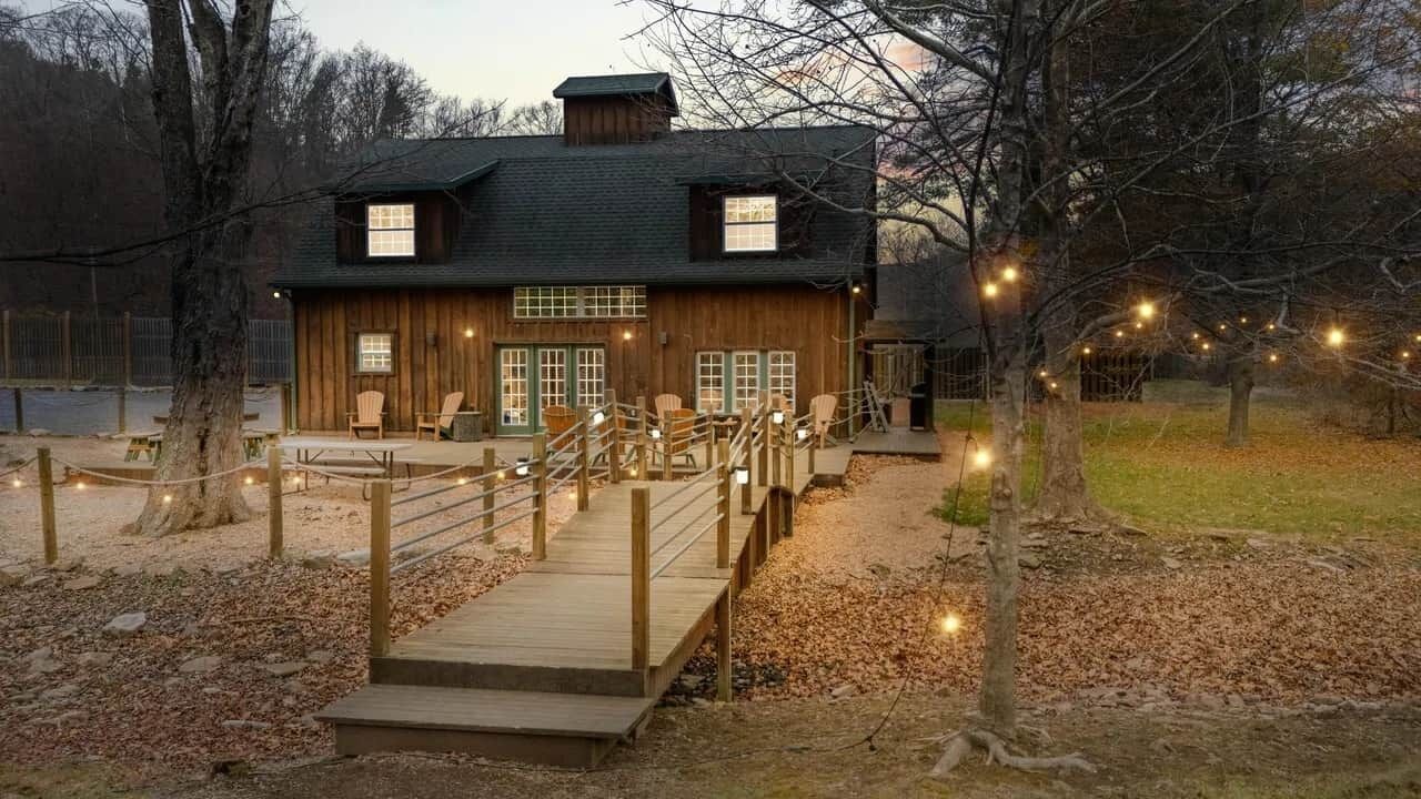 Een houten blokhut met terras, buitenmeubels en lichtjes.