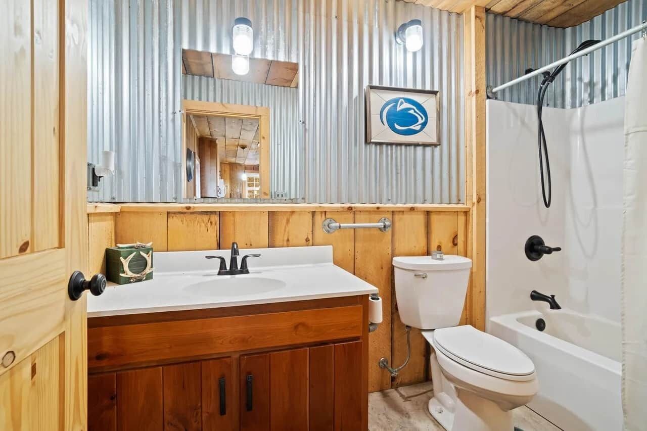 A bathroom with a wooden vanity, a toilet, and a bathtub.