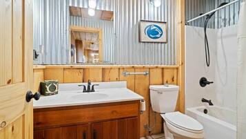 A bathroom with a wooden vanity, a toilet, and a bathtub.