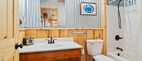 A bathroom with a wooden vanity, a toilet, and a bathtub.