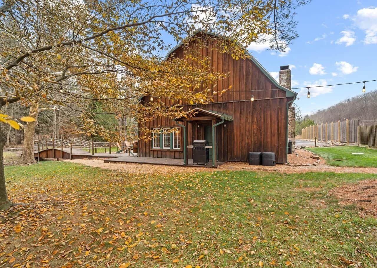 A rustic barn-style building with a wooden exterior, a green door, and a small porch area.