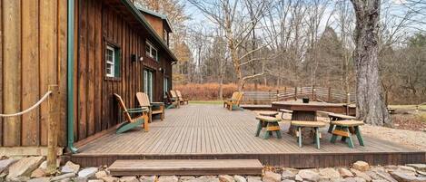 A wooden building with a deck, outdoor seating, and a stone pathway.