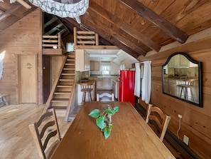 Un interior de madera con una mesa de comedor, sillas, una escalera y una zona de cocina.