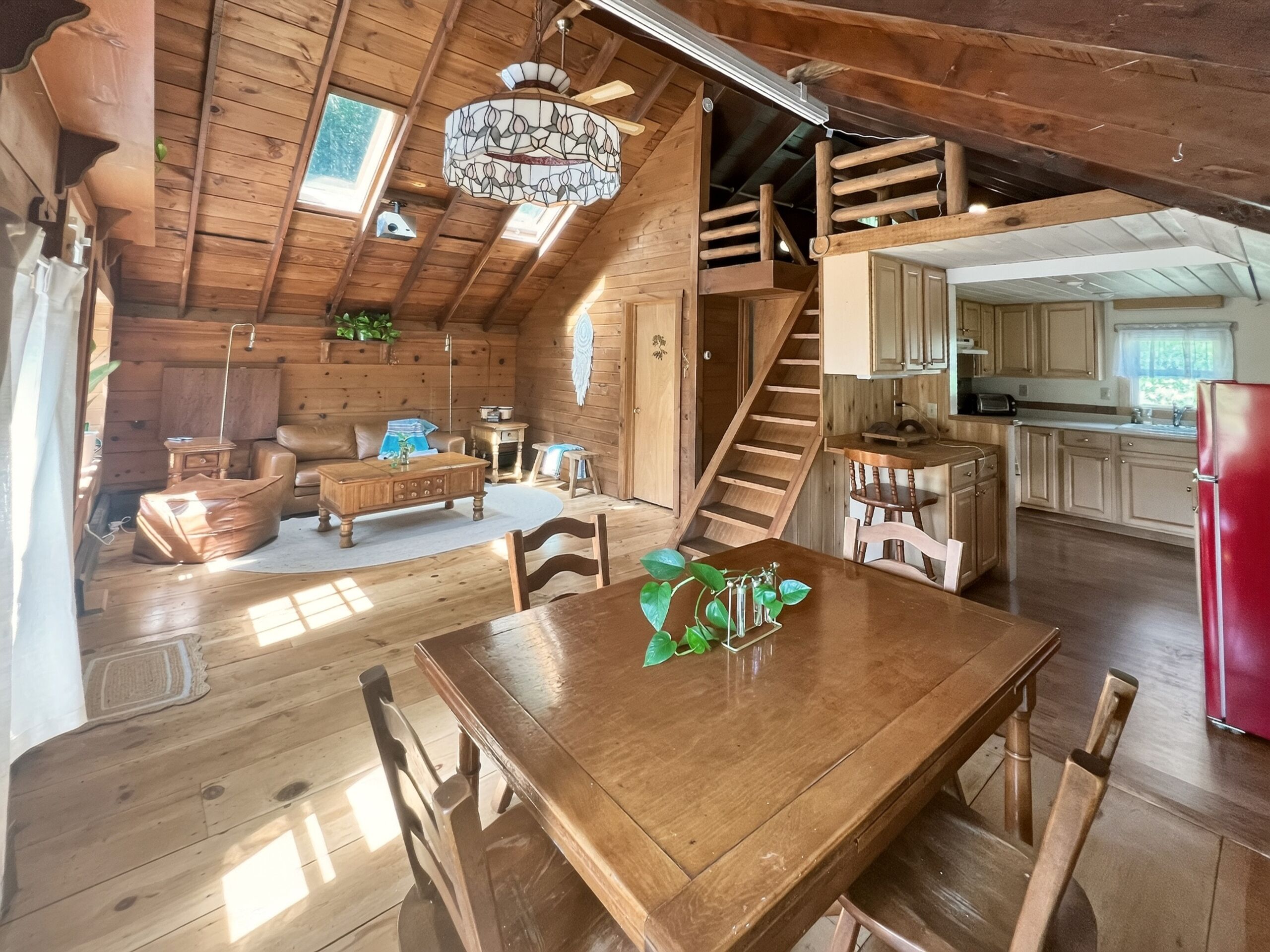 L’intérieur d’une cabane en bois comprend un coin repas, une cuisine et un escalier menant à un niveau supérieur.
