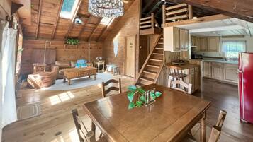 L’intérieur d’une cabane en bois comprend un coin repas, une cuisine et un escalier menant à un niveau supérieur.