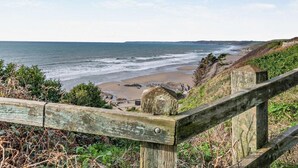 Blick auf die Küste mit Holzzaun, Strand und Meer.