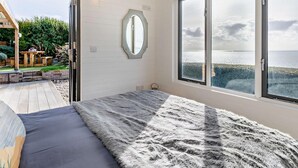 Ein Schlafzimmer mit einem großen Bett, einem Spiegel und Meerblick.