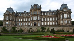 A large, historic building with symmetrical architecture, multiple windows, and a formal garden with hedges and flower beds. - 3 Bed in Barnard Castle (oc-93880) (Middleton-in-Teesdale)