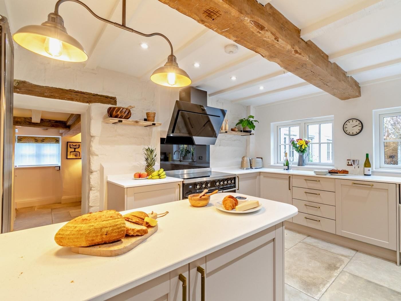 A modern kitchen with a central island, wooden beams, and pendant lighting.