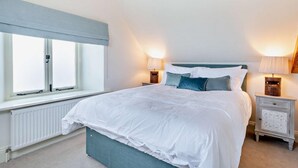 Un dormitorio con una cama grande, dos mesitas de noche con lámparas, una decoración con estrellas y una ventana con persianas.