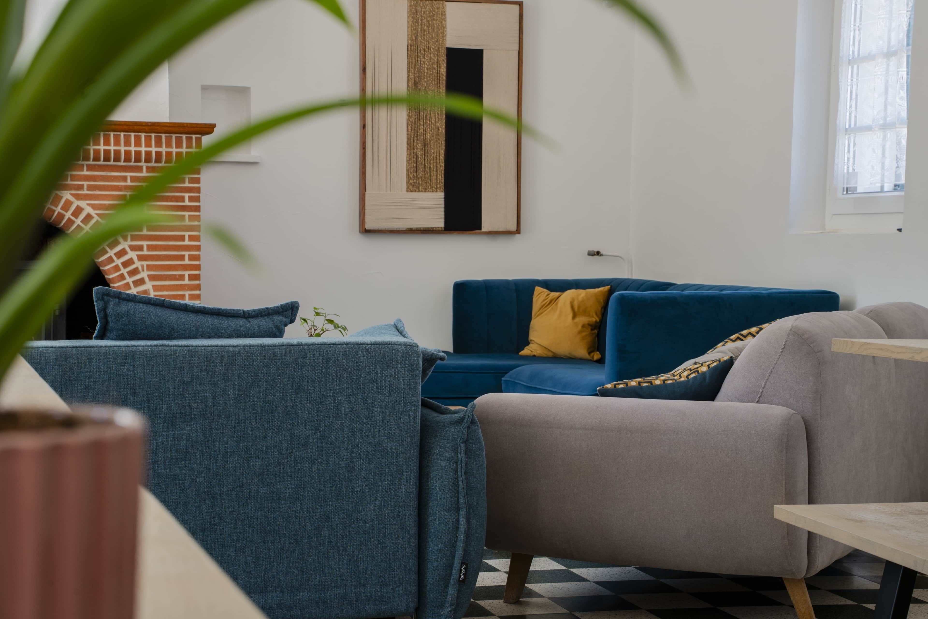 Ein Wohnzimmer mit einem blauen Sofa, einem grauen Sessel und einem Holztisch.