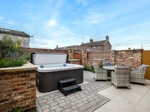 Ein Whirlpool, Korbstühle und eine Backsteinmauer in einem Garten.