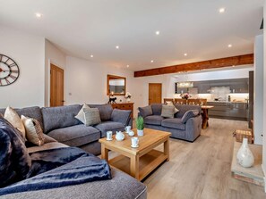 A modern living room with two grey sofas, a wooden coffee table, and a dining area with a wooden table and chairs. - 3 Bed in York (oc-93897) (Tollerton)