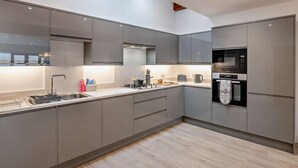 Eine moderne Küche mit grauen Schränken, Edelstahlgeräten und Holzboden.