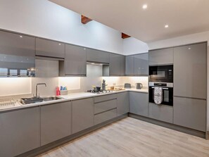 A modern kitchen with grey cabinetry, stainless steel appliances, and a wooden floor. - 3 Bed in York (oc-93897) (Tollerton)