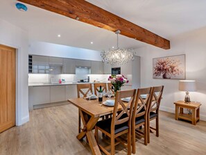 Eine moderne Küche mit Essbereich, Holzbalken, einer Kristallleuchter und einem Gemälde an der Wand.