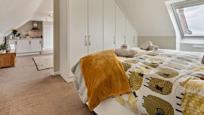 A bedroom with a sloped ceiling, a bed with a patterned duvet, a white wardrobe, and a skylight. - 1 Bed in Blandford Forum (oc-93922) (Spetisbury)