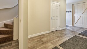 A hallway with carpeted stairs, a white door, and a wooden floor. - 1 Bed in Blandford Forum (oc-93922) (Spetisbury)