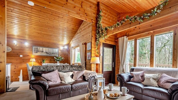 Ein Holzblockhaus-Innenraum mit zwei Sofas, einem Couchtisch und einem Esstisch.