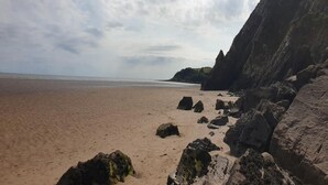 Ein Strand mit großen Felsen und einer Klippe.
