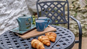 A round metal table with a blue teapot, two blue cups, and croissants on a wooden board. - 2 Bed in Brixham (oc-93990) (Brixham)