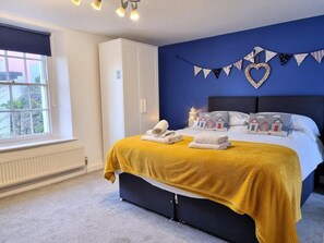 A hotel room with a bed, a window, a wardrobe, and a wall with a heart-shaped decoration. - 2 Bed in Brixham (oc-93990) (Brixham)