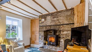 A cozy living room with a stone fireplace, a television, and comfortable seating.