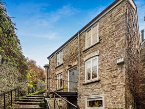 A stone building with a staircase leading to a landing, surrounded by vegetation. - 2 Bed in Brecon (oc-92729) (Brecon)