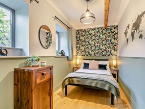 A bedroom with a bed, a dresser, a mirror, a hanging light, and a floral wallpaper. - 6 Bed in Huddersfield (oc-93984) (Huddersfield)