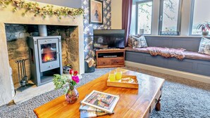 A cozy living room with a fireplace, a television, a sofa, and a coffee table with a tray of orange juice. - 6 Bed in Huddersfield (oc-93984) (Huddersfield)