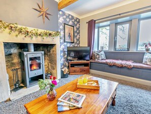 A cozy living room with a fireplace, a television, a sofa, and a coffee table with a tray of orange juice. - 6 Bed in Huddersfield (oc-93984) (Huddersfield)