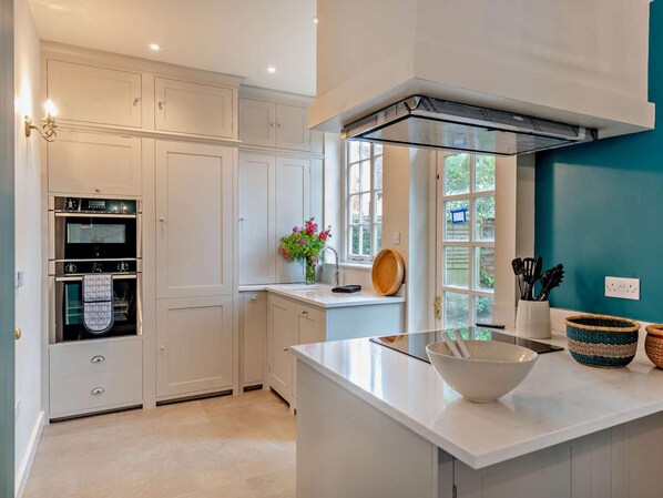 A modern kitchen with built-in appliances, a large window, and a teal accent wall.
