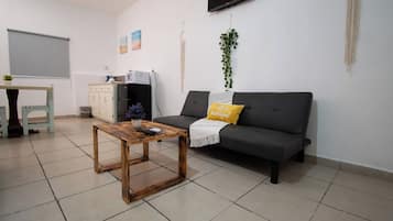 Una sala de estar con un sofá, una mesa de centro, un televisor y una planta pequeña.