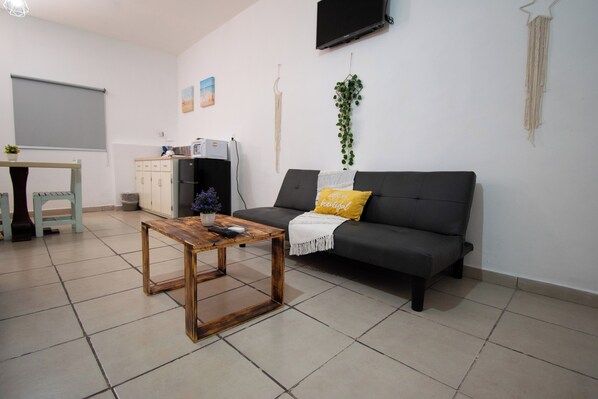 A living room with a sofa, a coffee table, a TV, and a small plant. - Isla Venados Renta Vacacional (Mazatlán)