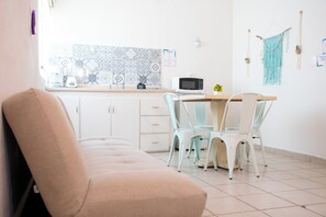 A modern kitchen with white cabinets, a microwave, and a window with patterned tiles.