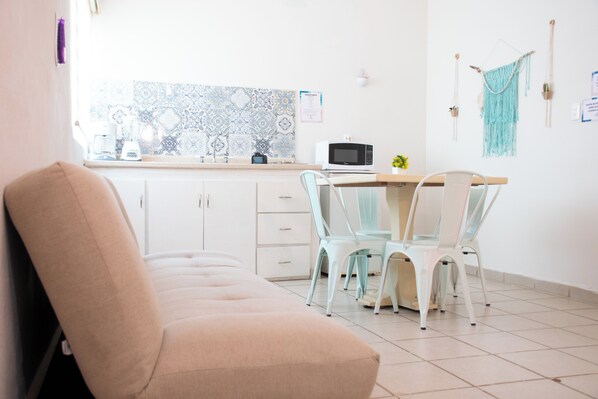Una cocina moderna con armarios blancos, un microondas y un ventanal con azulejos decorativos.
