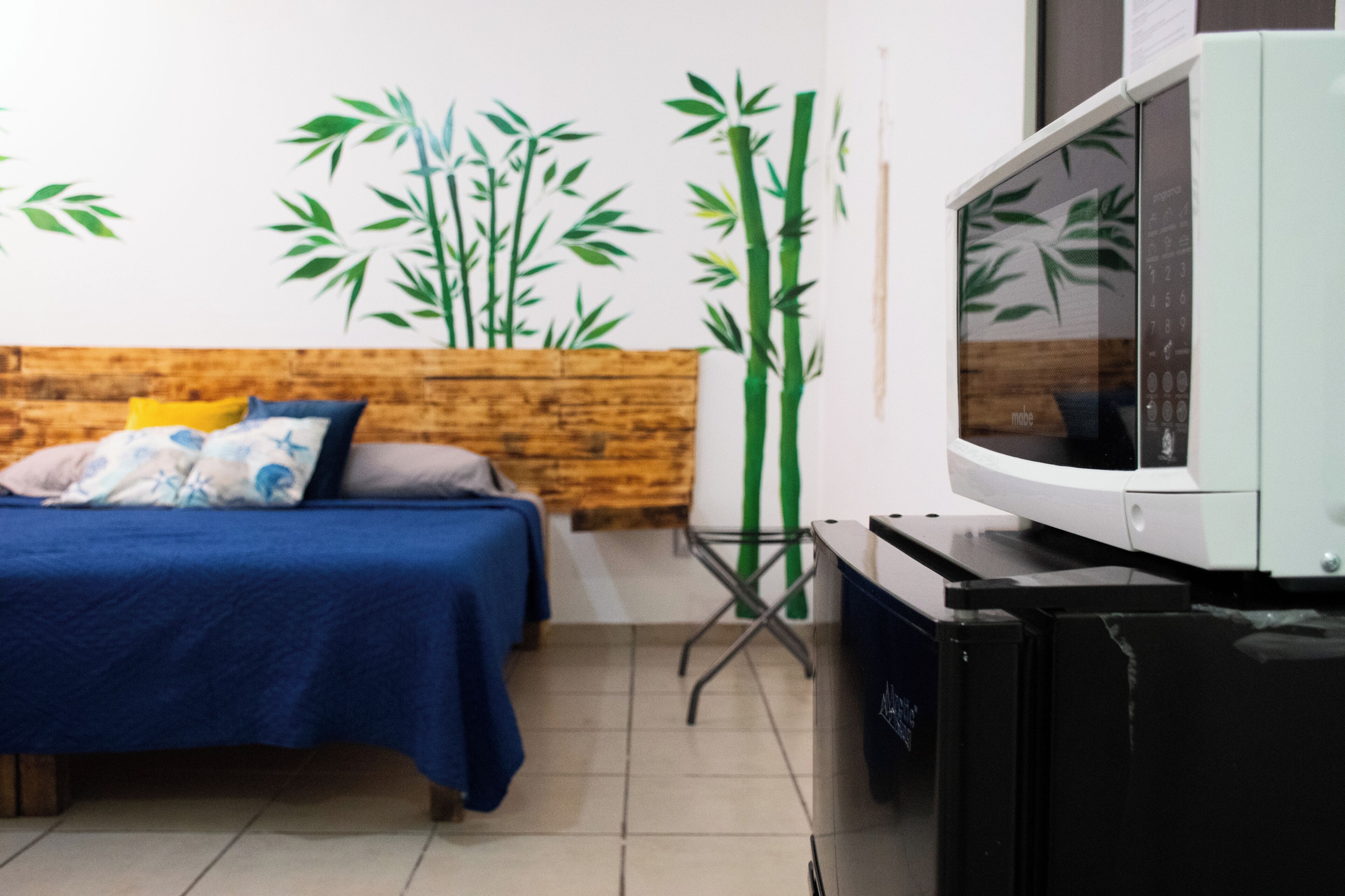 Een kamer met een bed, een houten hoofdbord, een televisie en een wand met bamboe-decoraties.